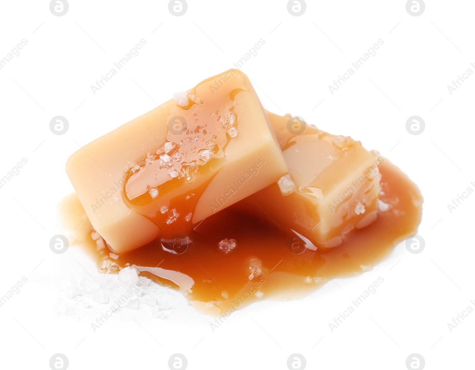 Photo of Yummy caramel candies and sea salt isolated on white