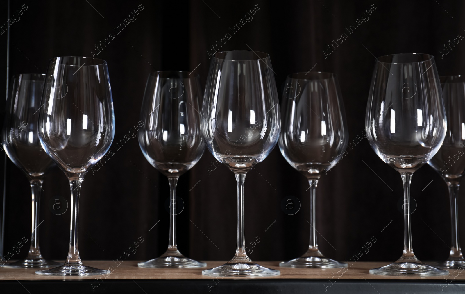 Photo of Empty wine glasses on shelf against black background