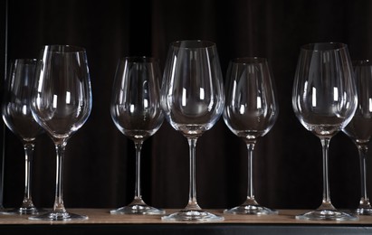 Photo of Empty wine glasses on shelf against black background