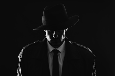 Photo of Old fashioned detective in hat on dark background, black and white effect