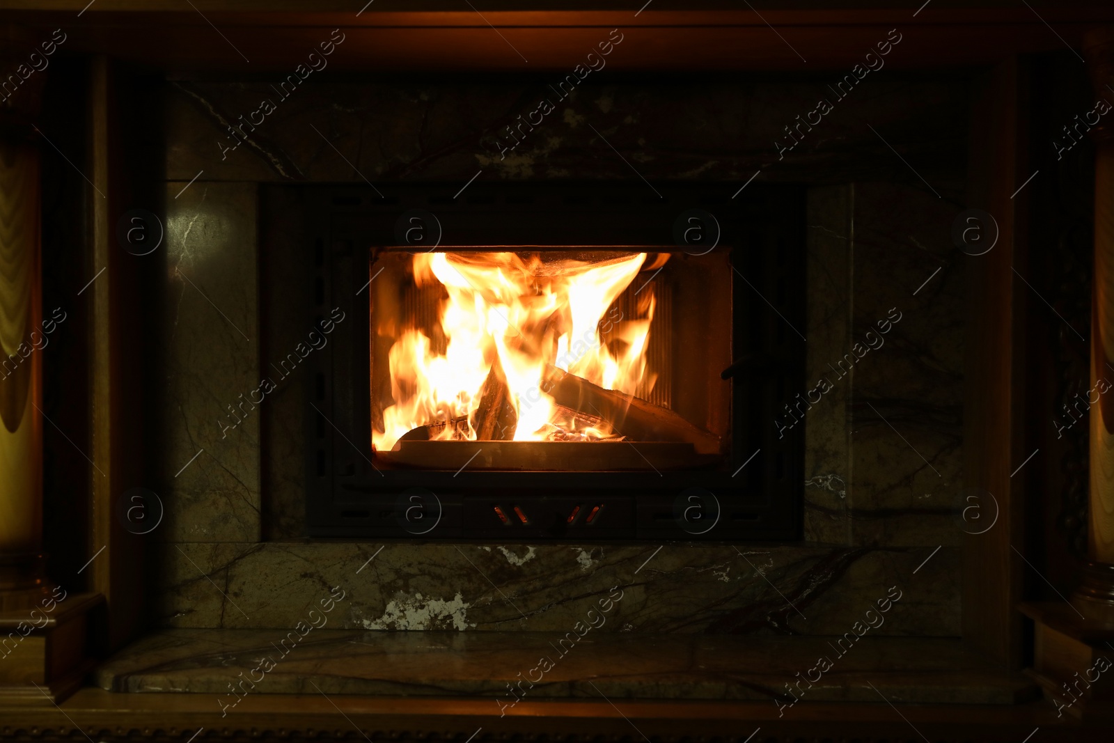 Photo of Fireplace with burning wood in darkness indoors