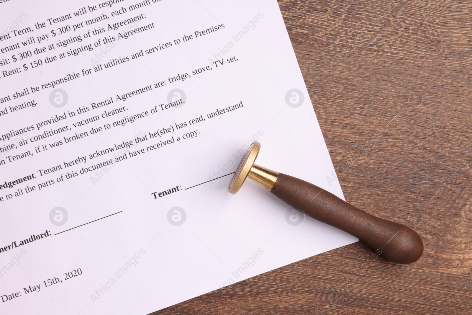 Photo of One stamp tool and document on wooden table, top view