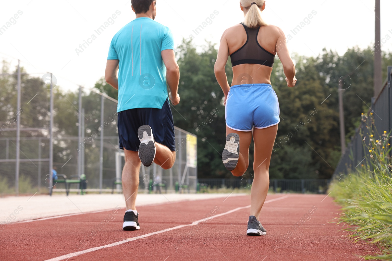 Photo of Healthy lifestyle. Sporty couple running at stadium, back view