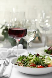 Photo of Delicious salad and wine served on table in restaurant