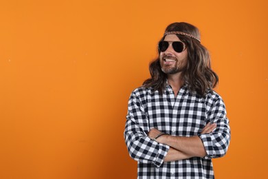 Hippie man in sunglasses on orange background, space for text