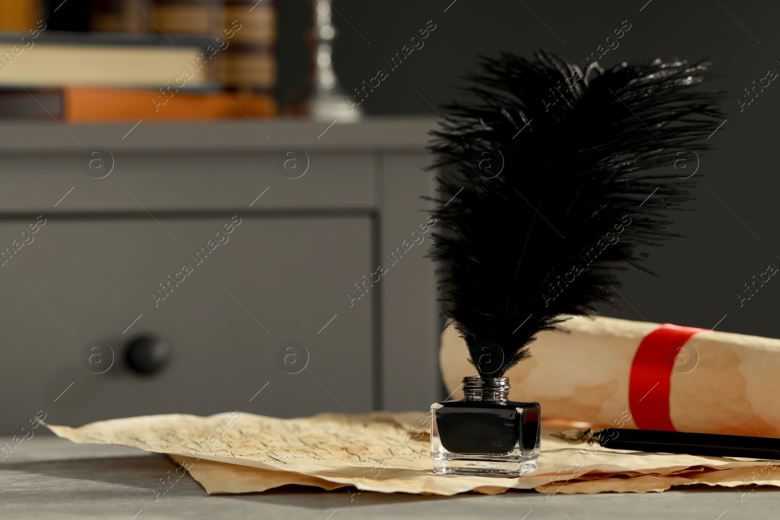 Photo of Inkwell with feather, fountain pen and vintage parchment on grey textured table indoors. Space for text