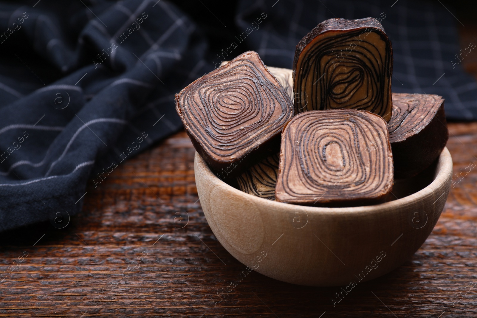Photo of Bowl of tasty chocolate candies on wooden table. Space for text