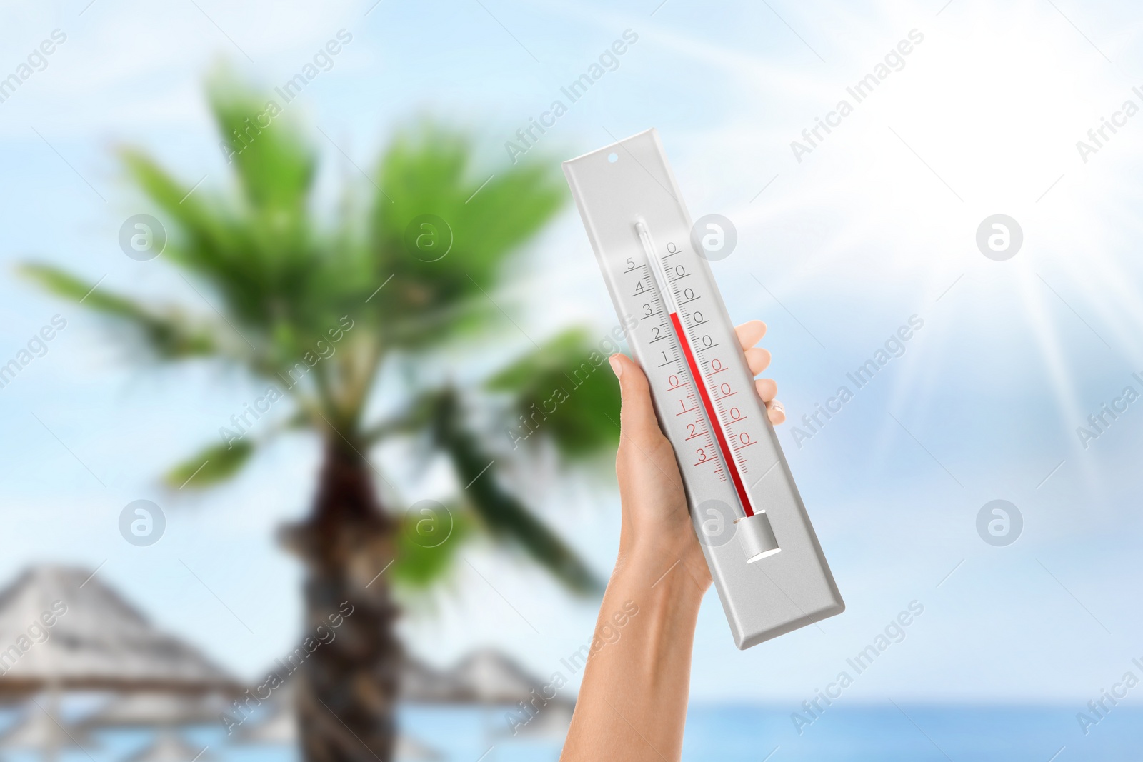 Image of Woman holding thermometer on beach in summer, closeup