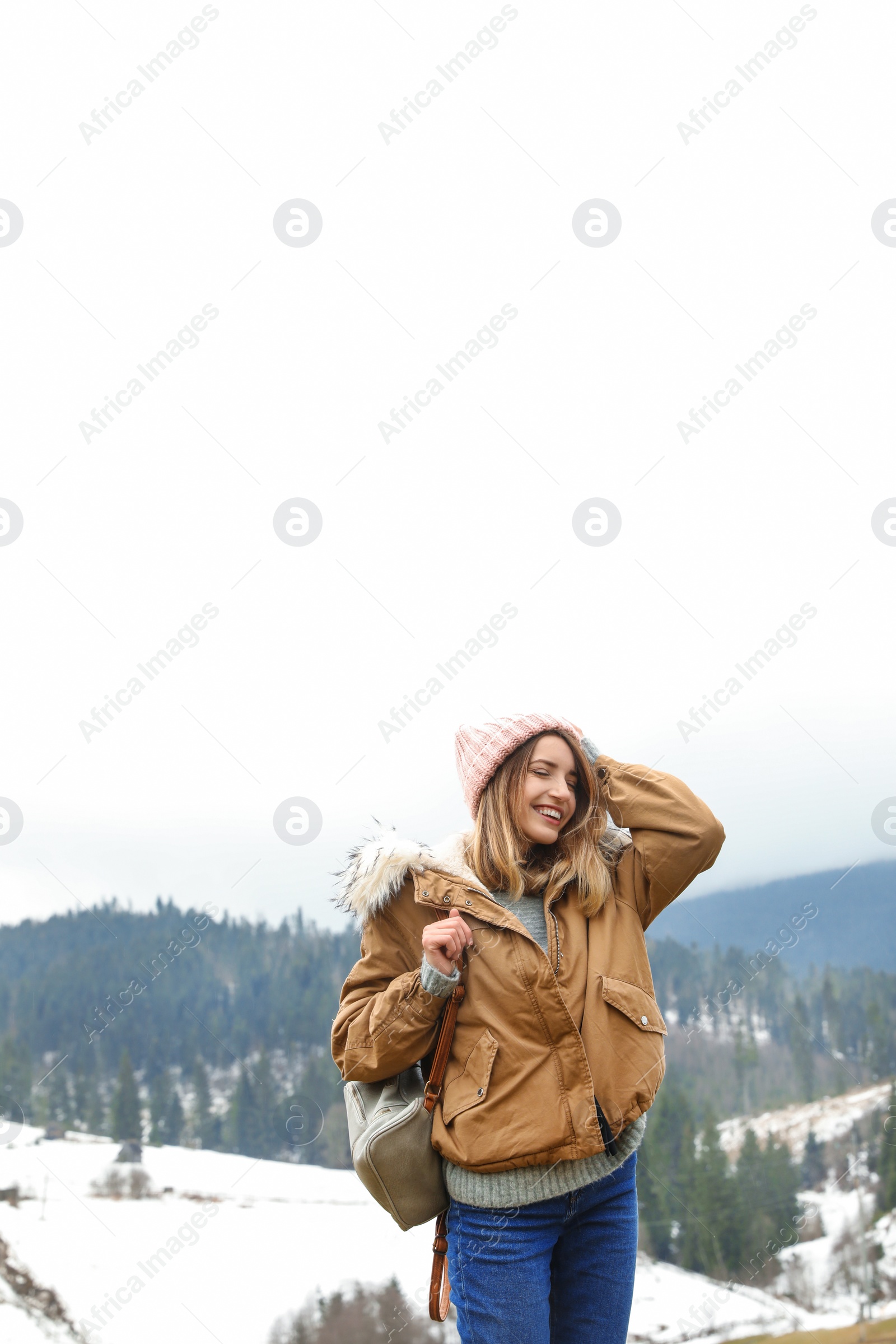 Photo of Young woman in warm clothes near snowy hill. Winter vacation