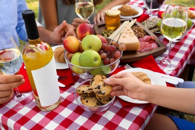 Photo of Young woman with cookie at picnic table outdoors, closeup