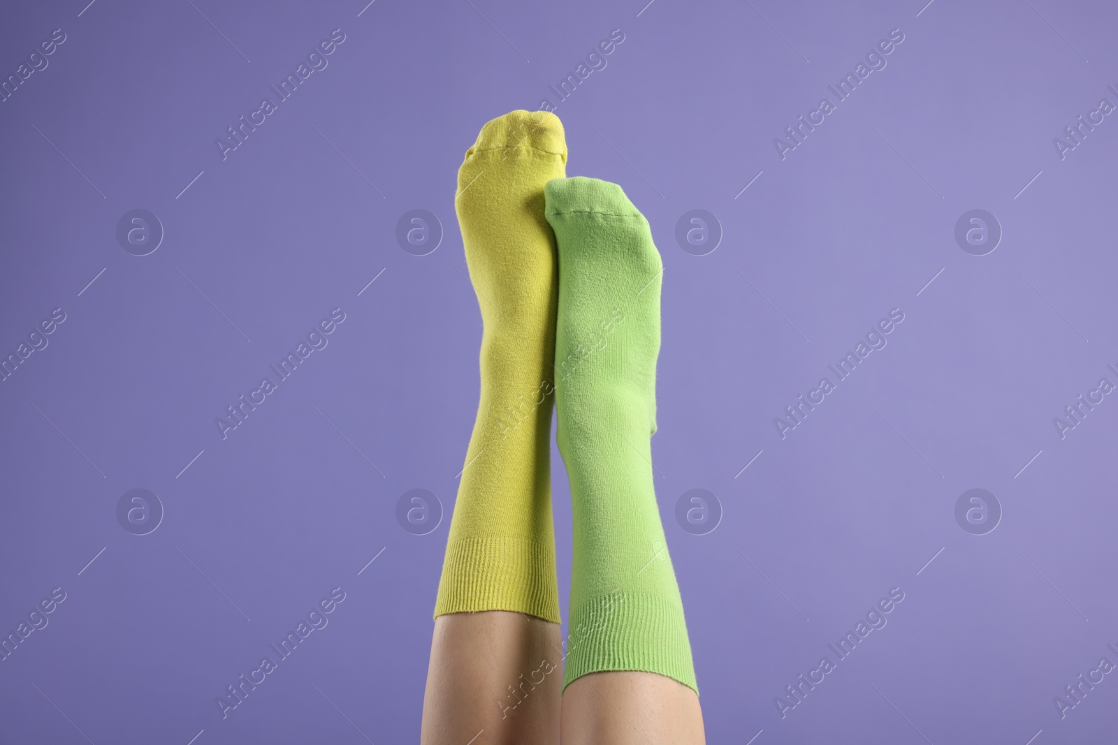 Photo of Woman in different stylish socks on violet background, closeup