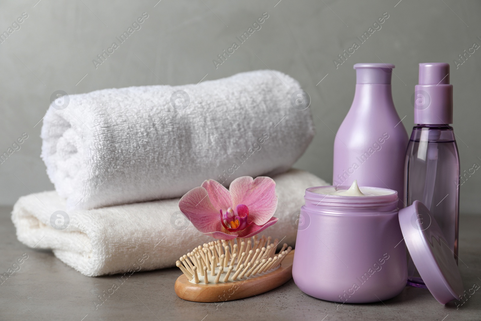 Photo of Different hair products, flower and brush on grey table