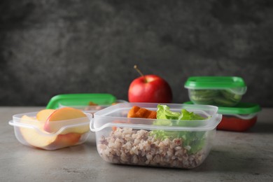 Photo of Set of plastic containers with fresh food on light grey table