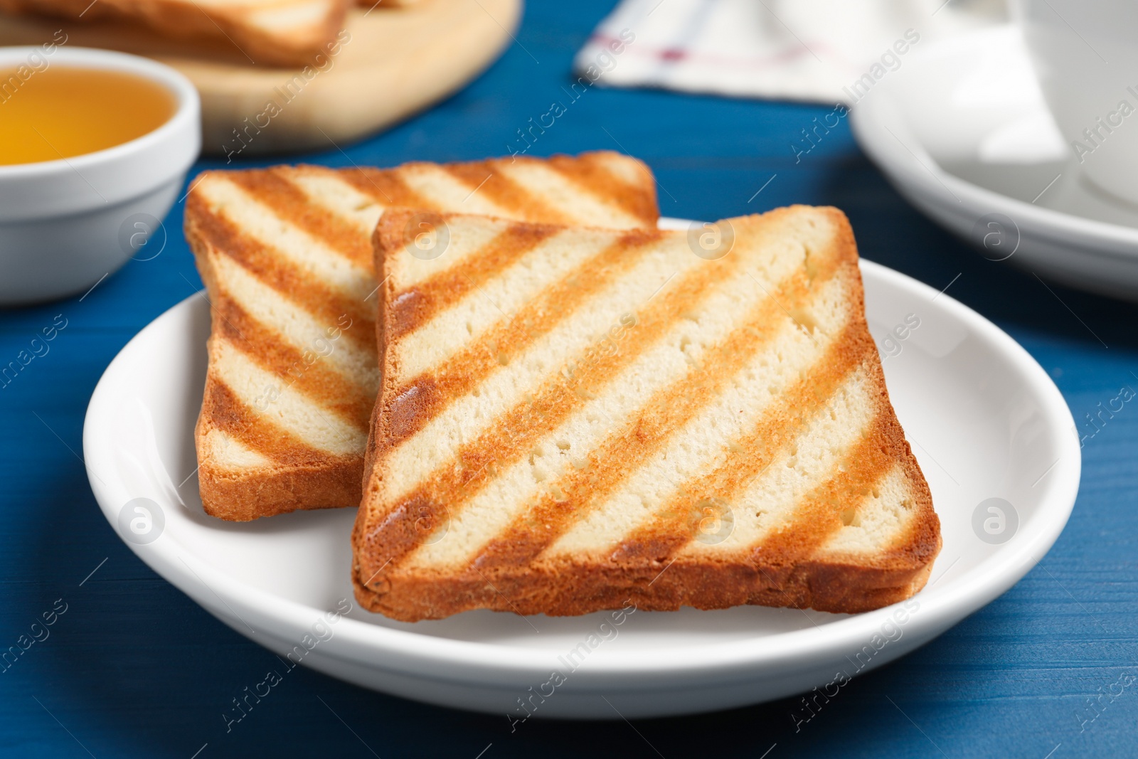 Photo of Slices of tasty toasted bread on blue wooden table, closeup