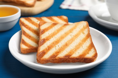 Slices of tasty toasted bread on blue wooden table, closeup