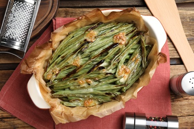 Photo of Delicious baked green beans on wooden table, flat lay