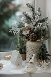 Many beautiful Christmas decorations and fir branches on window sill indoors