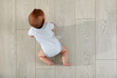 Photo of Cute baby crawling on floor, top view