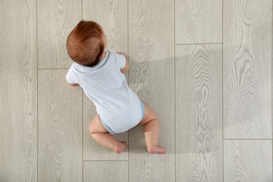 Cute baby crawling on floor, top view