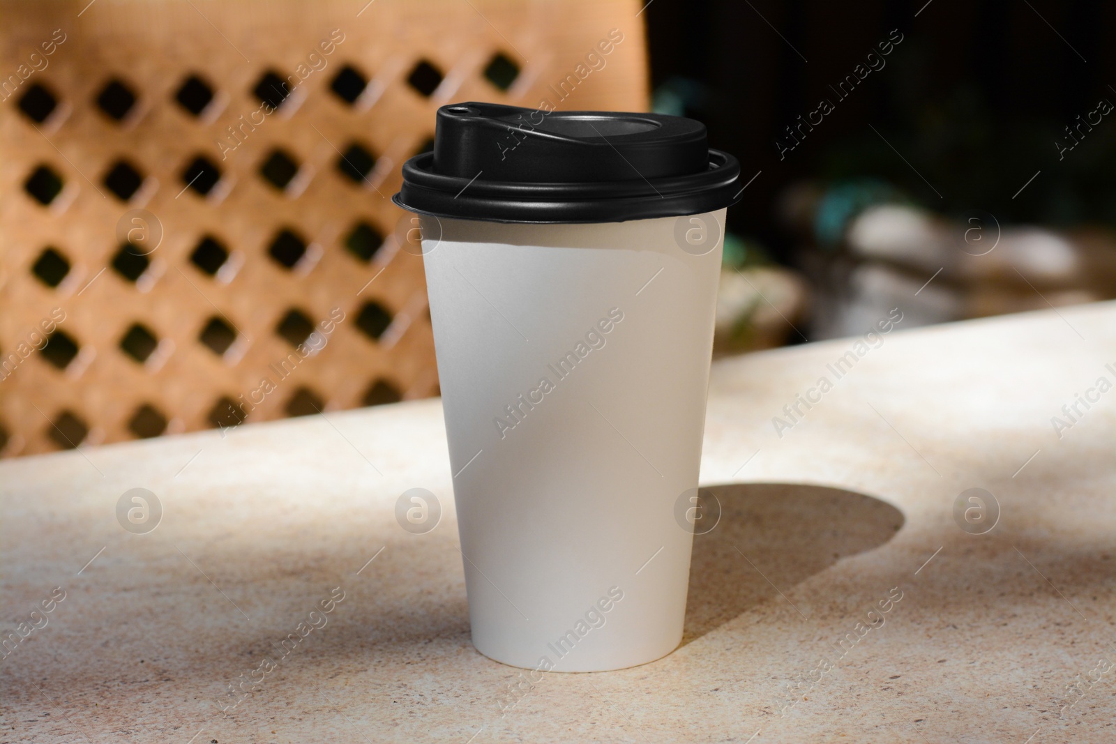 Photo of Takeaway coffee cup on beige table in cafe, space for text