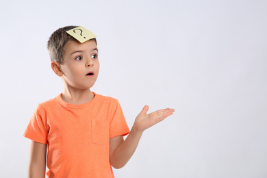 Photo of Emotional little boy with question mark on white background