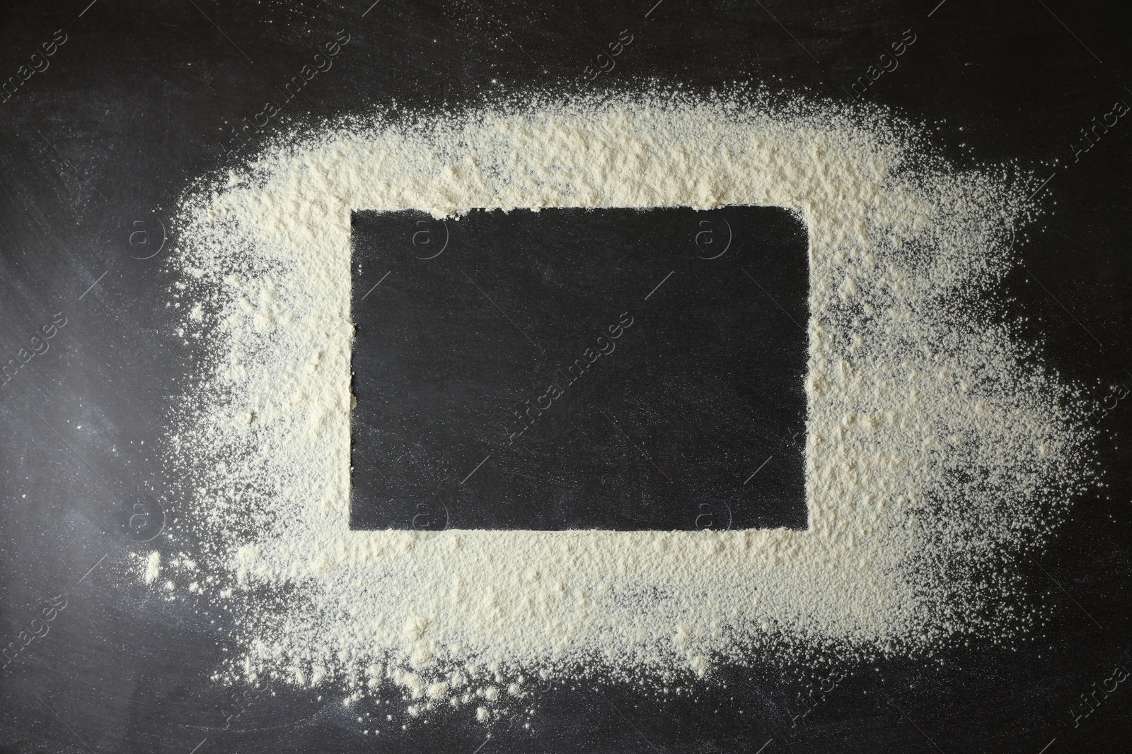 Photo of Frame made of flour on black table, top view. Space for text