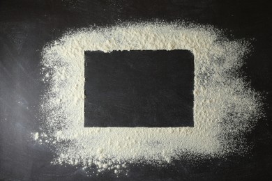 Frame made of flour on black table, top view. Space for text