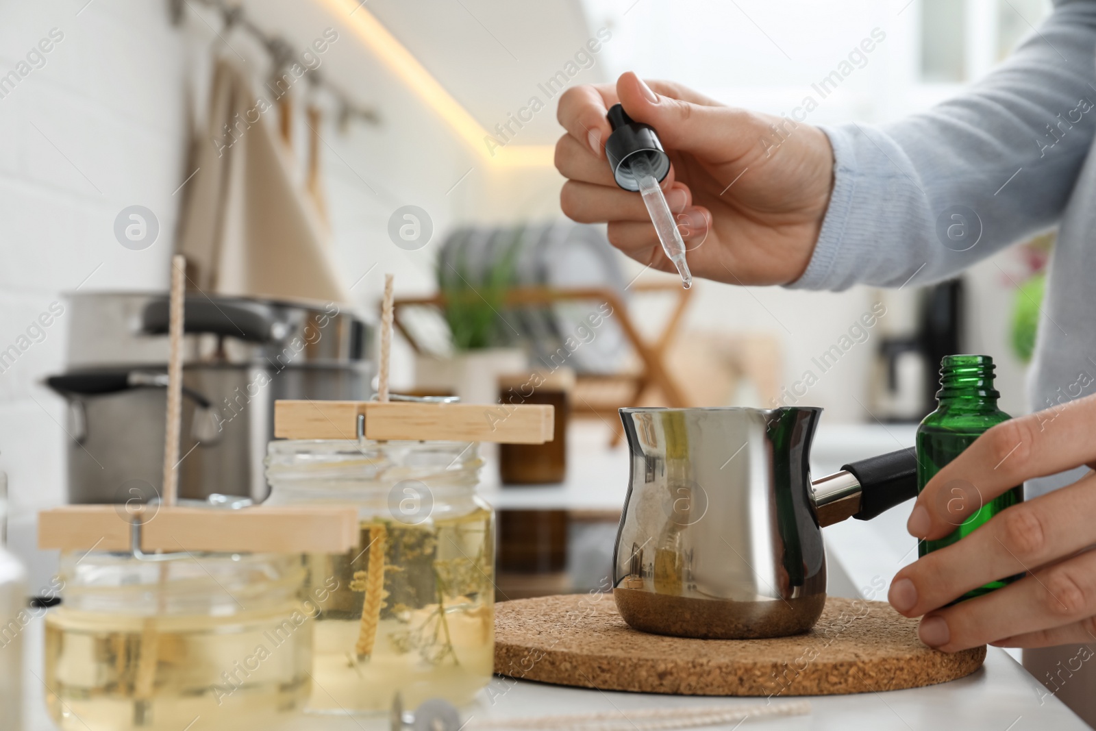 Photo of Woman making aromatic candles at white table indoors, closeup