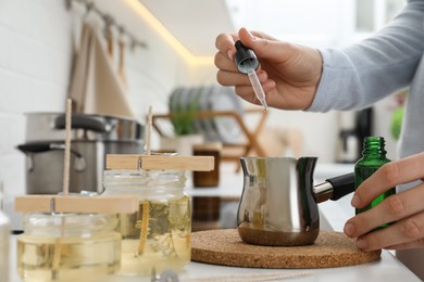 Woman making aromatic candles at white table indoors, closeup