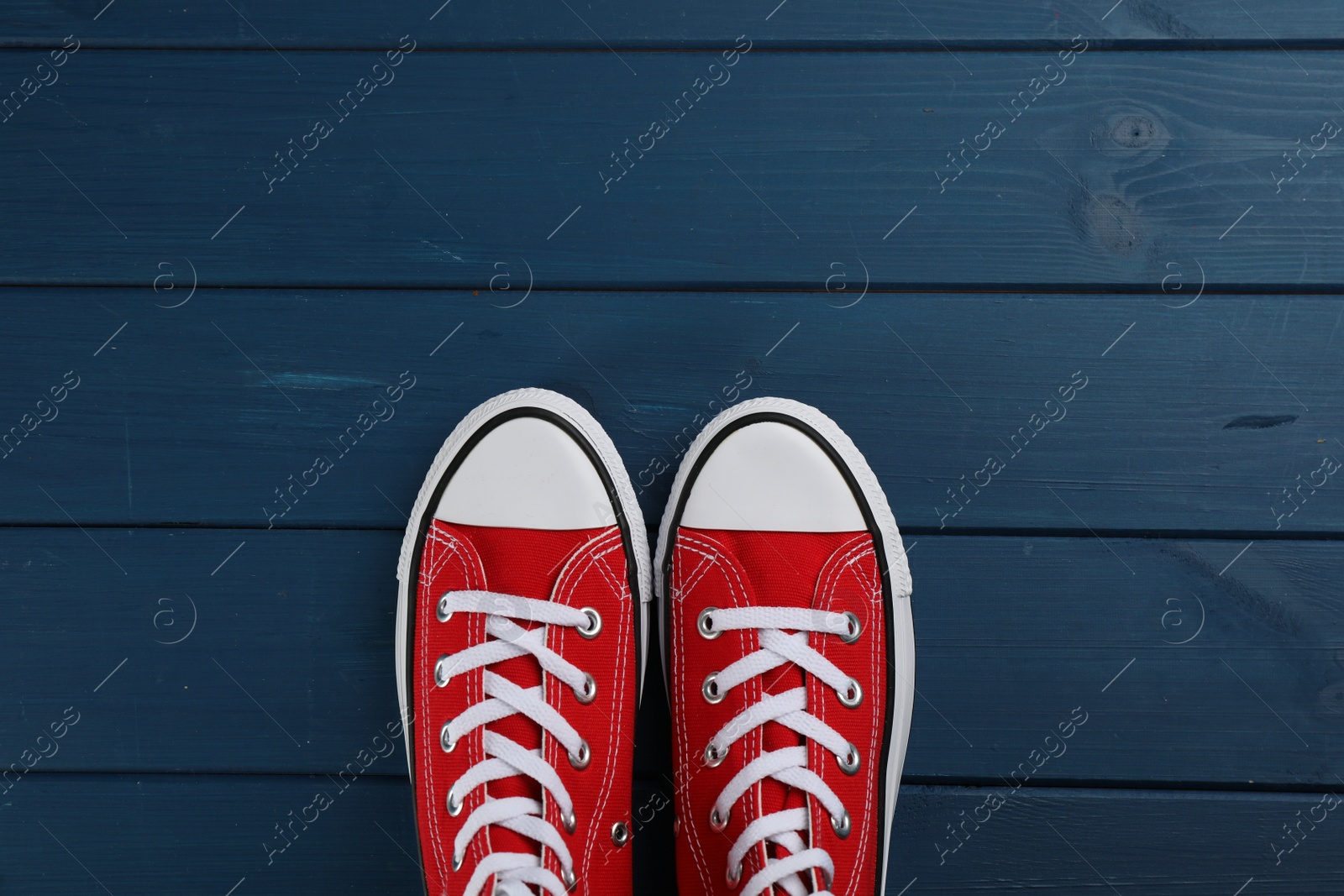 Photo of Pair of red sneakers on blue wooden table, flat lay