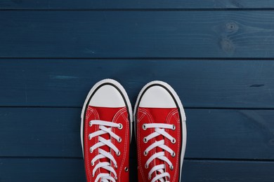 Photo of Pair of red sneakers on blue wooden table, flat lay