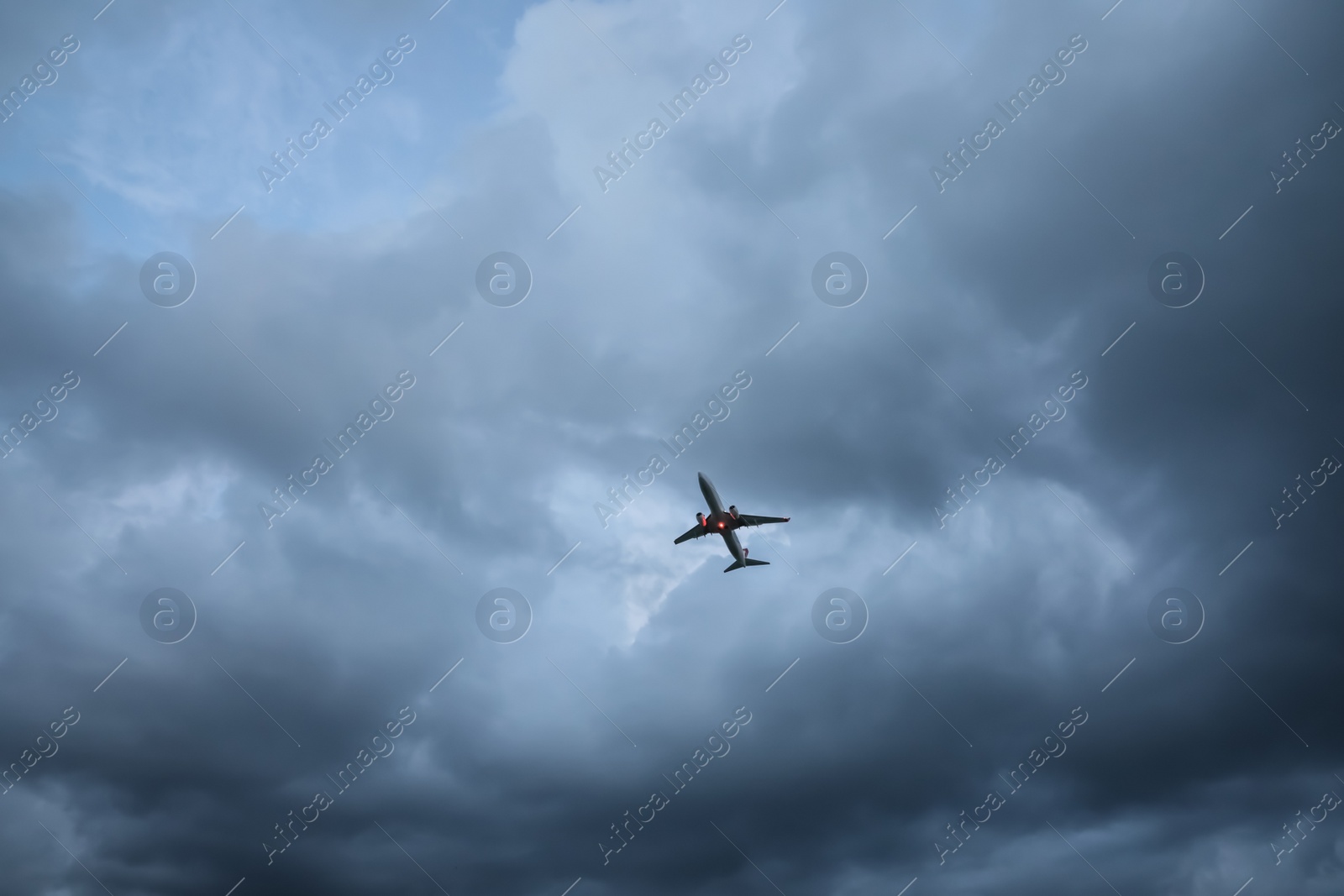 Photo of Modern white airplane flying in sky with clouds, low angle view