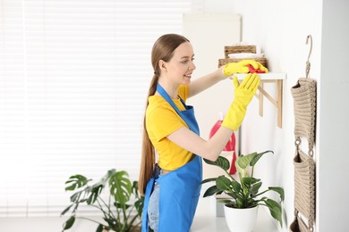 Photo of Woman cleaning shelf with rag at home, space for text