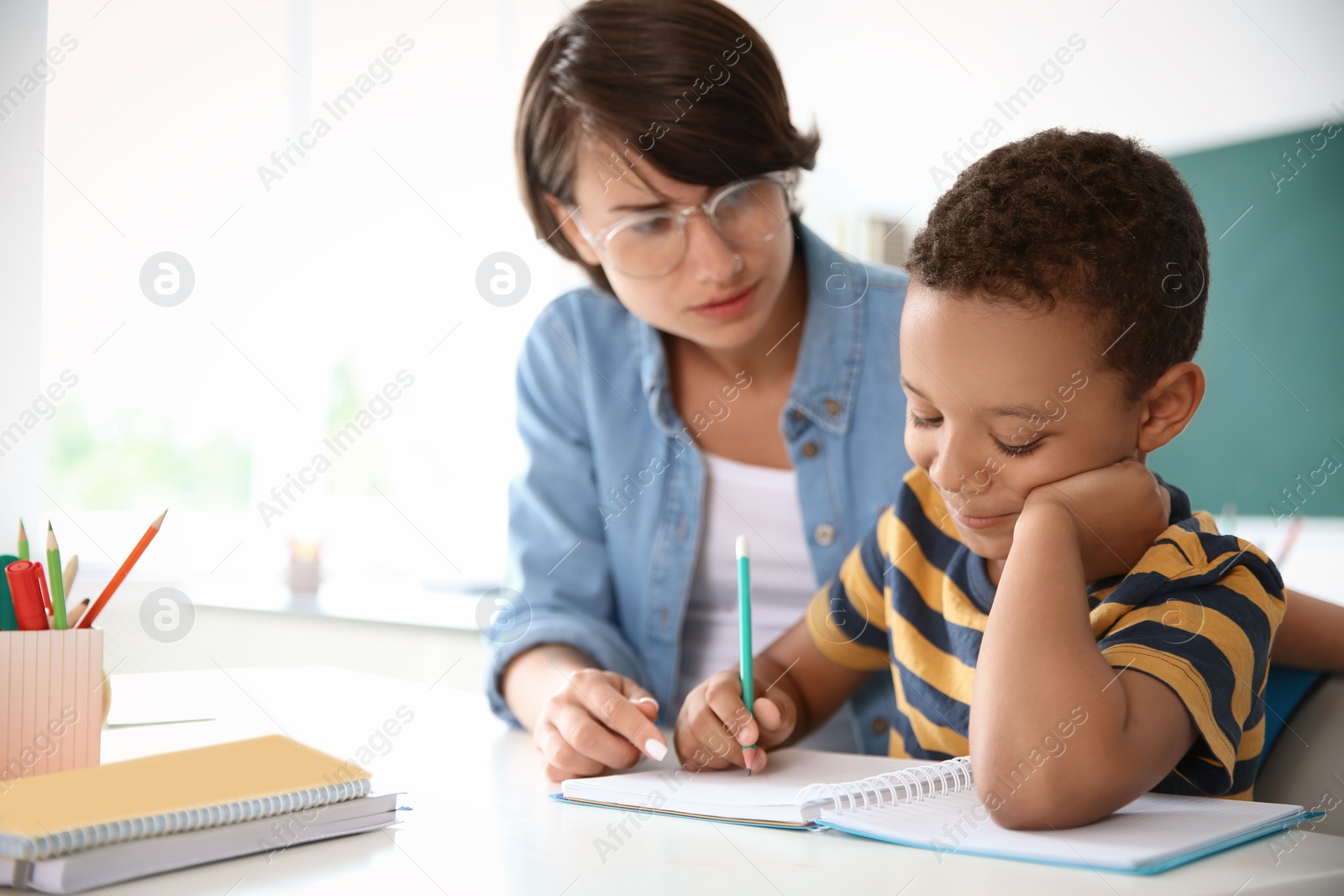 Photo of Female teacher helping child with assignment at school