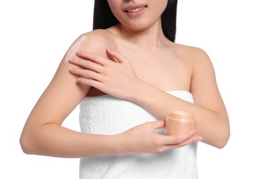 Young woman applying body cream onto shoulder on white background, closeup