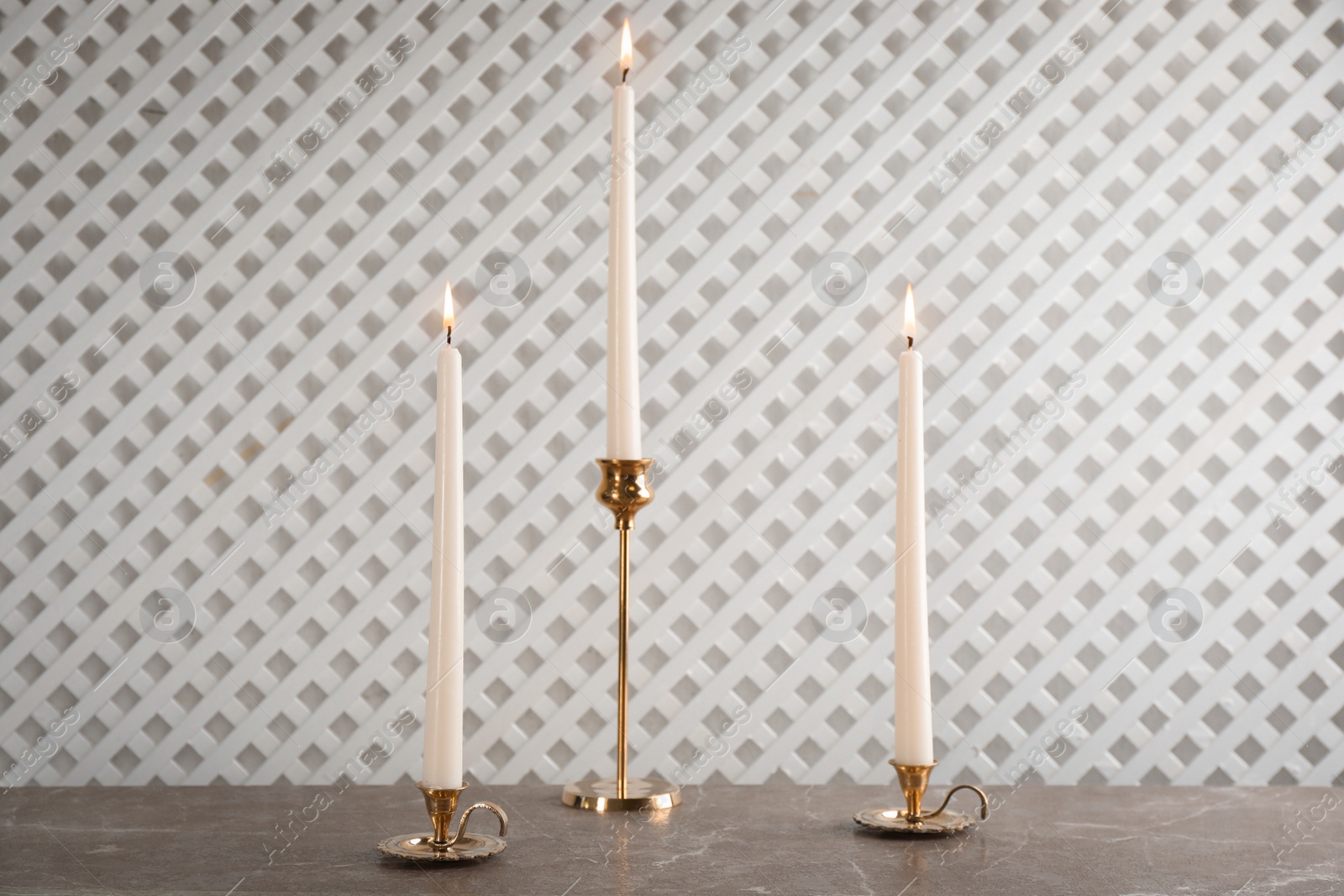 Photo of Elegant candlesticks with burning candles on marble table