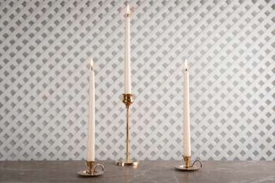 Elegant candlesticks with burning candles on marble table