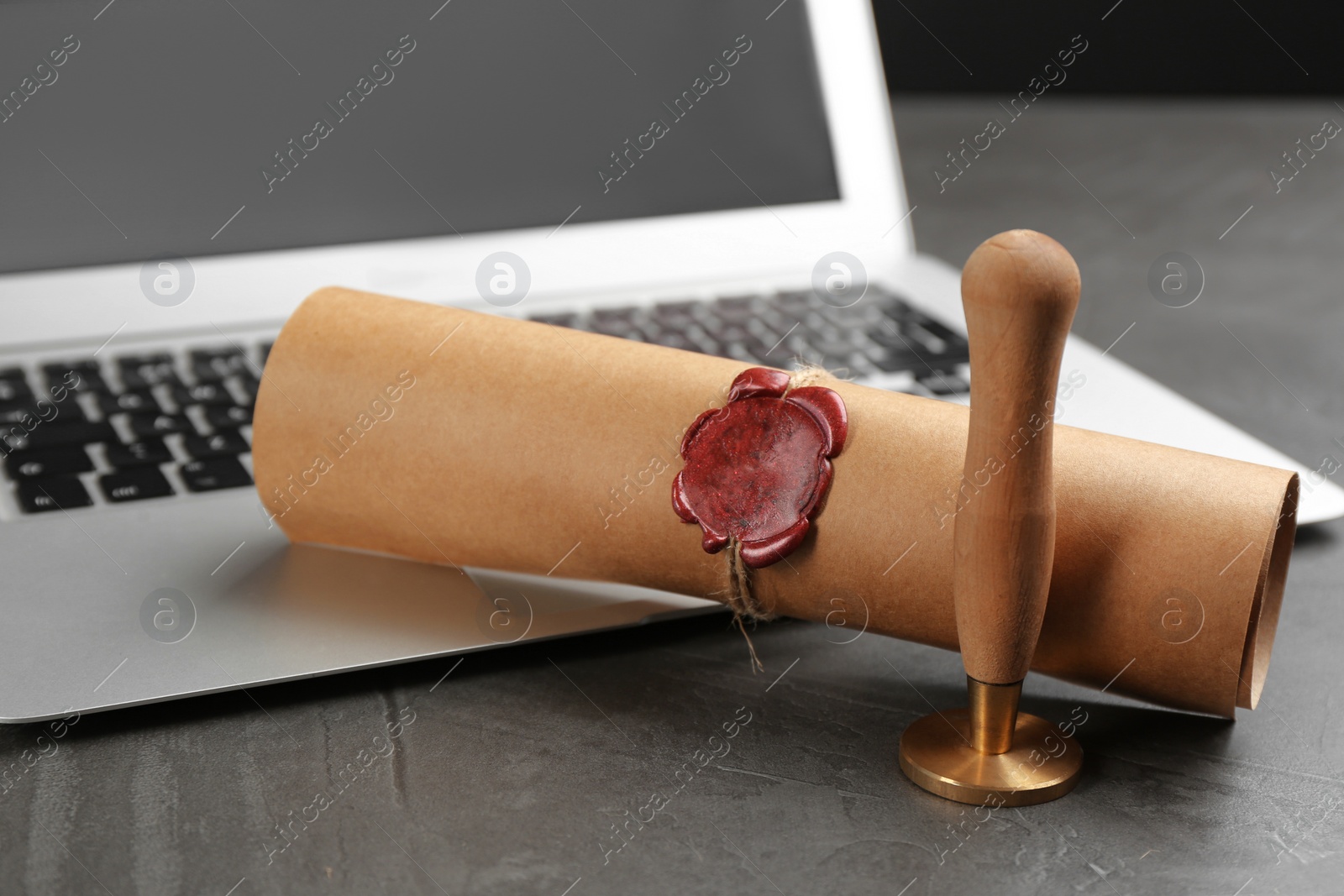 Photo of Notary's public pen and sealed document near laptop on grey stone table, closeup