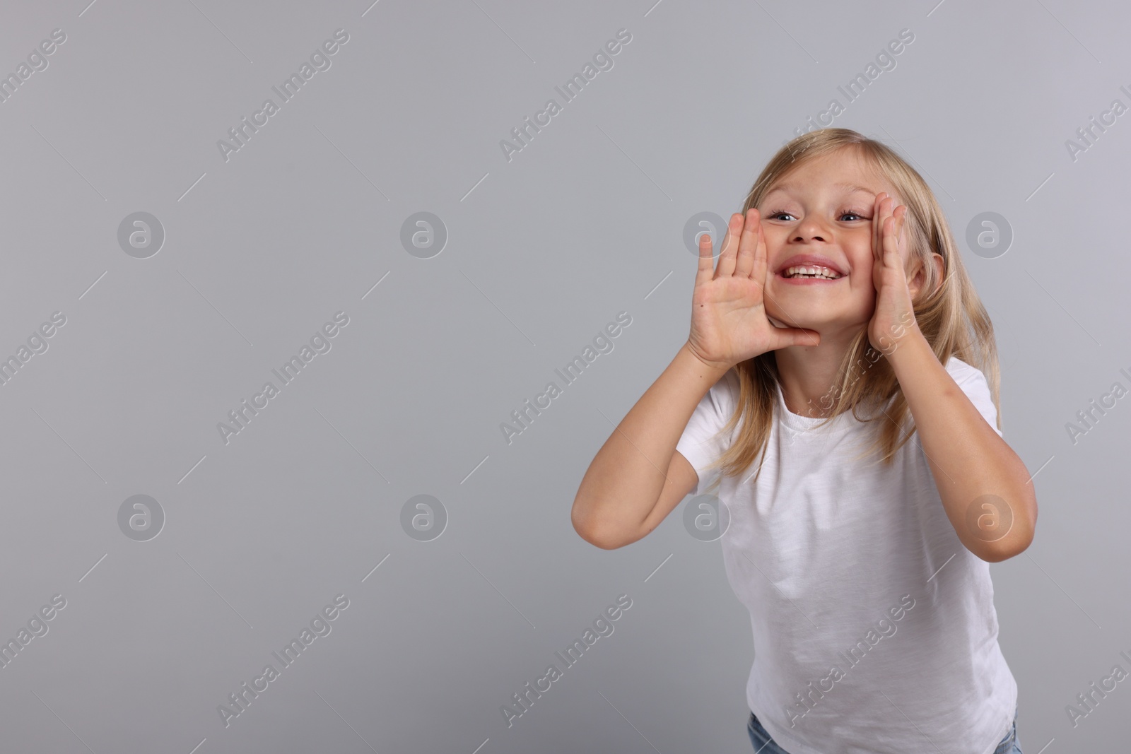 Photo of Special promotion. Little girl shouting to announce information on grey background. Space for text