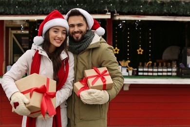 Photo of Lovely couple with Christmas presents at winter fair