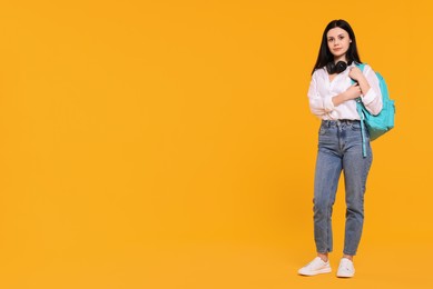 Photo of Student with backpack and headphones on yellow background. Space for text