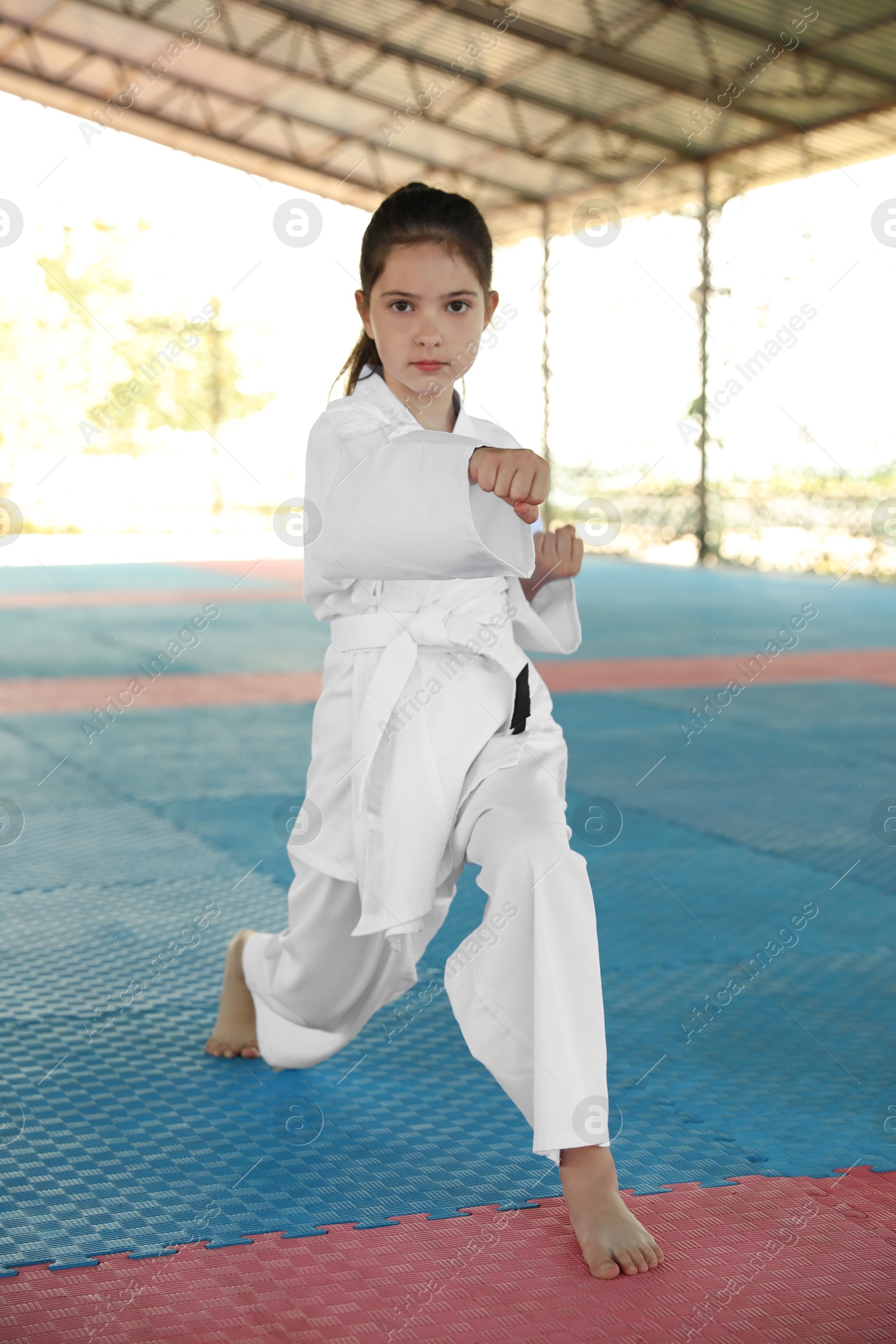 Photo of Girl in kimono practicing karate on tatami outdoors