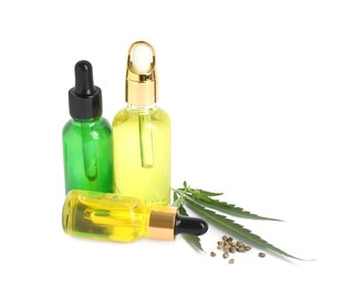 Photo of Bottles of hemp oil, leaves and seeds on white background