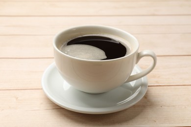 Photo of Cup of aromatic coffee on light wooden table, closeup