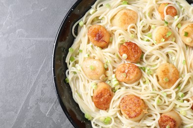 Photo of Delicious scallop pasta with green onion on grey table, top view