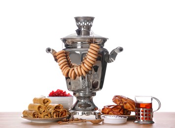 Photo of Traditional Russian samovar and treats on wooden table against white background