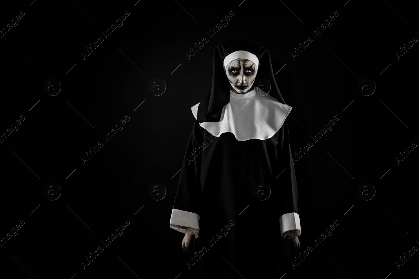 Photo of Portrait of scary devilish nun on black background, space for text. Halloween party look