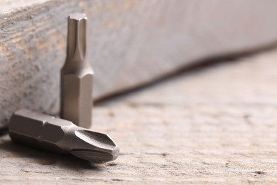 Photo of Different screwdriver bits on wooden table, closeup. Space for text