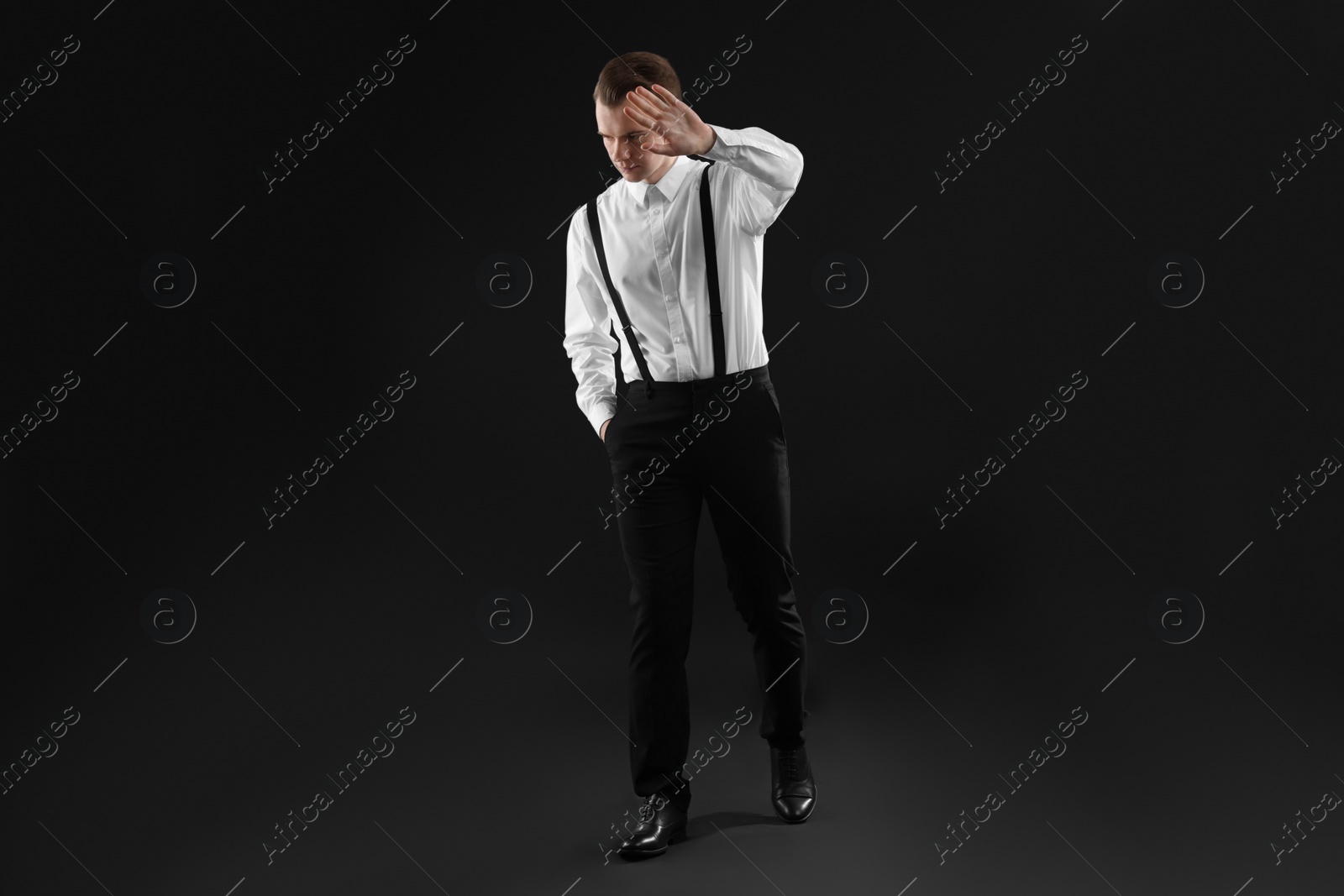 Photo of Young man covering face with hand on black background