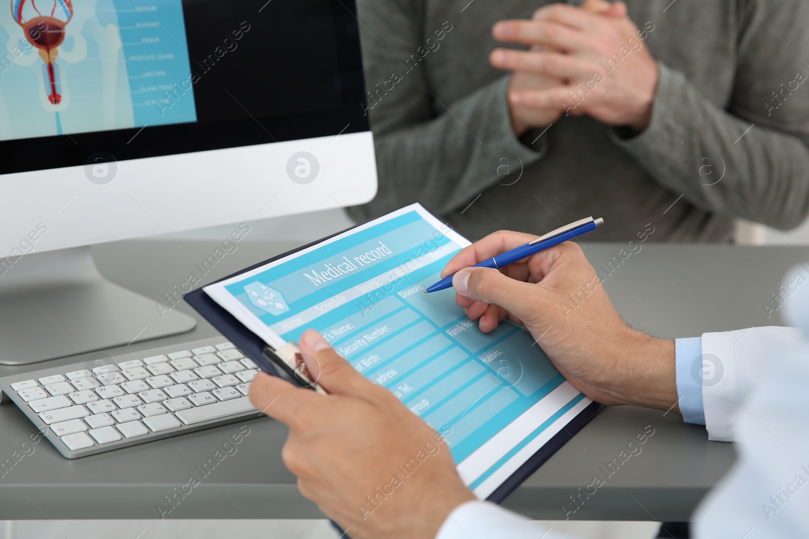 Photo of Young urologist filling medical record at table in hospital